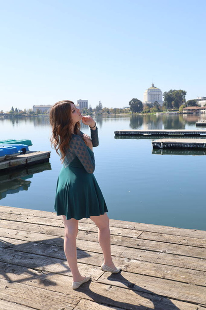 Photo of a Beautiful white girl in a beautiful dress in front of a lake - Foto, afbeelding