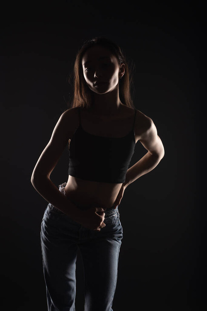 Casual dressed silhouette of beautiful and young girl is posing in studio - Zdjęcie, obraz