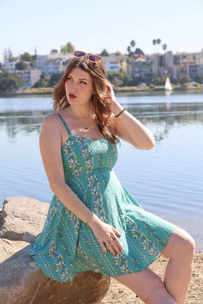 Photo of a Beautiful white girl in a beautiful dress in front of a lake - Photo, image