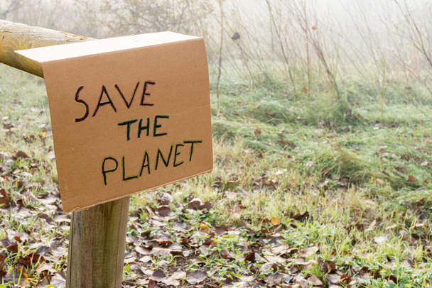 Pappschild an einem Holzgeländer mit dem Slogan "Rettet den Planeten" - Foto, Bild
