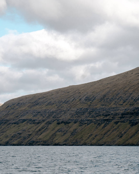 A vertical shot of a mountain at the sea on a cloudy day in the Faroe Islands. - Foto, imagen