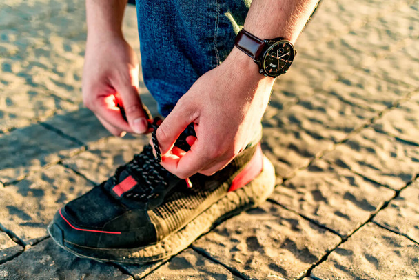A closeup shot of a male tying shoelaces outdoors - Zdjęcie, obraz