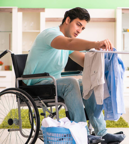 Tekerlekli sandalyedeki engelli adam çamaşır yıkıyor - Fotoğraf, Görsel