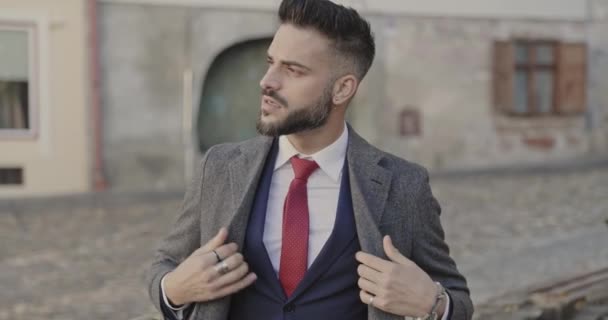 hombre de negocios guapo ajustando su abrigo, mirando a un lado con actitud fresca - Metraje, vídeo