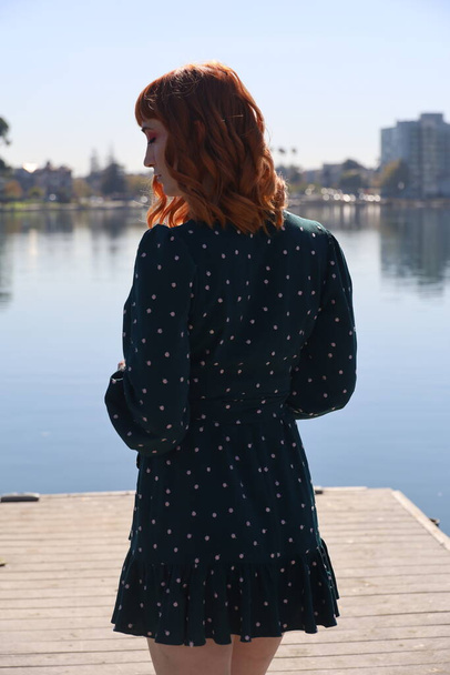 Photo of a Beautiful white girl in a beautiful dress standing in front of a lake - Фото, изображение