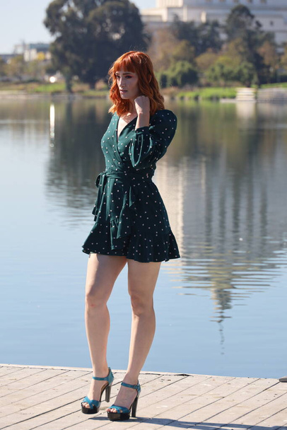 Photo of a Beautiful white girl in a beautiful dress standing in front of a lake - Фото, зображення