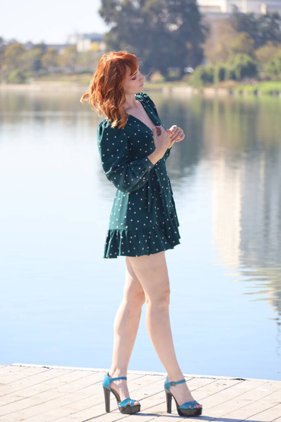 Photo of a Beautiful white girl in a beautiful dress standing in front of a lake - Foto, imagen
