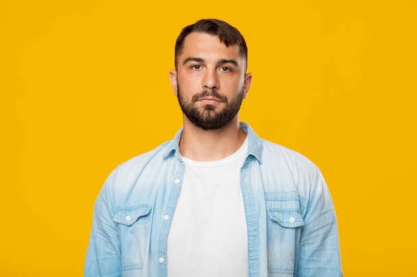 Serious calm mature european man with beard in casual look at camera, isolated on yellow background - Photo, image