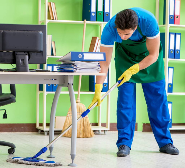 Άνδρας όμορφος επαγγελματίας καθαριστής κάνει σφουγγάρισμα στο γραφείο - Φωτογραφία, εικόνα