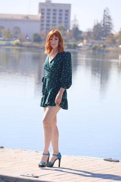 Photo of a Beautiful white girl in a beautiful dress standing in front of a lake - Foto, Bild