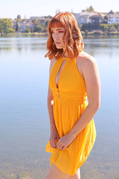 Photo of a Beautiful white girl in a beautiful dress standing in front of a lake - Foto, immagini