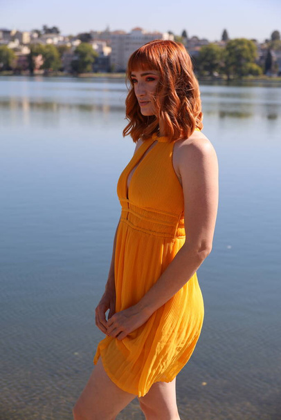 Фото красивой белой девушки в красивом платье, стоящем перед озером - Фото, изображение