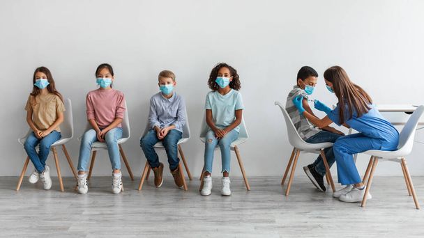 Diverse Kids Getting Vaccinated Against Covid-19 Sitting Over Gray Background - Photo, Image
