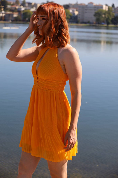Photo of a Beautiful white girl in a beautiful dress standing in front of a lake - Zdjęcie, obraz