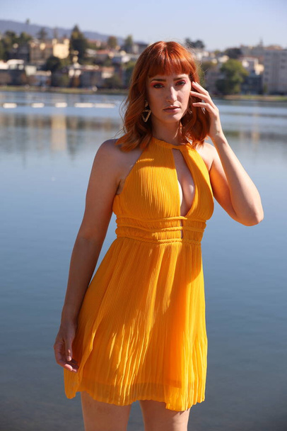 Photo of a Beautiful white girl in a beautiful dress standing in front of a lake - Photo, Image