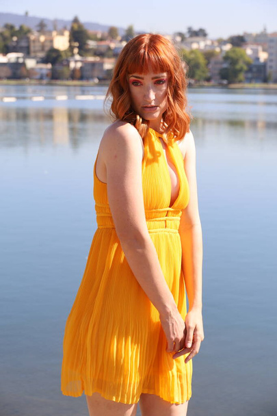 Photo of a Beautiful white girl in a beautiful dress standing in front of a lake - Foto, Imagem