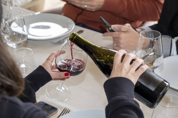 hand filling wine glass at dinner - Фото, изображение