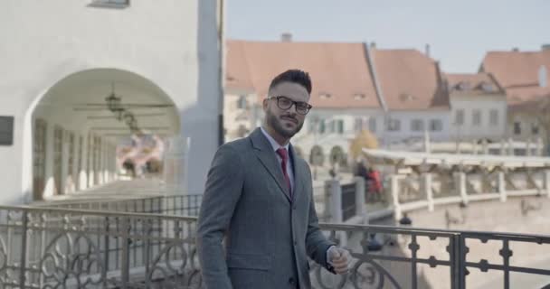 glücklicher junger Geschäftsmann mit Brille und Koffer geht, dreht und lächelt selbstbewusst in Sibiu, Siebenbürgen - Filmmaterial, Video