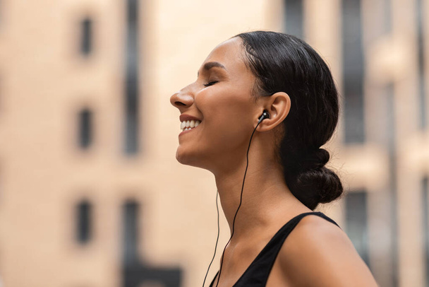 Playlist préférée. Happy Sporty Woman Écouter de la musique dans les écouteurs pendant l'entraînement en plein air - Photo, image