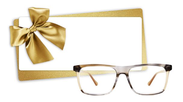 γυαλιά χριστουγεννιάτικη κάρτα δώρο, γυαλιστερή χρυσή κορδέλα τόξο για λαμπερό εισιτήριο, γυαλιά που απομονώνονται σε λευκό φόντο, αντίγραφο πρότυπο χώρο για διαφημιστικά και εμπορικά banner ή πώληση ετικέτα προσφοράς τιμής - Φωτογραφία, εικόνα