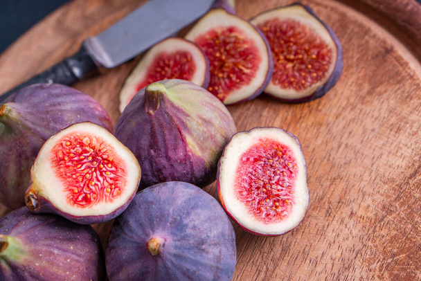 Organiczne słodkie owoce figowe zdrowe wegańskie warzywa dieta jedzenie świeże dojrzałe czerwone cut slide w pół smaczne pyszne soczyste tropikalne odżywki zestaw kolekcja izolowane na rustykalnym białym tle - Zdjęcie, obraz
