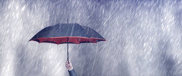 hombre de negocios sosteniendo paraguas en un día lluvioso - Foto, imagen