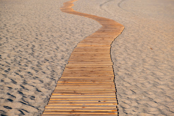 Strandpromenade. Holzplanken schlängeln sich auf einem leeren Fußweg am Sandstrand, griechische Insel Elafonissos, Sommerurlaub in Griechenland - Foto, Bild