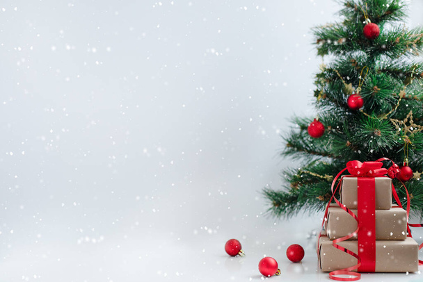 Θολή χριστουγεννιάτικο δέντρο, κουτιά δώρων και μπάλες. Ελαφρύ φόντο χιονιού. Χώρος για σχεδιασμό και κείμενο. Διακοπές, γιορτή και παρουσιάζει την έννοια. - Φωτογραφία, εικόνα
