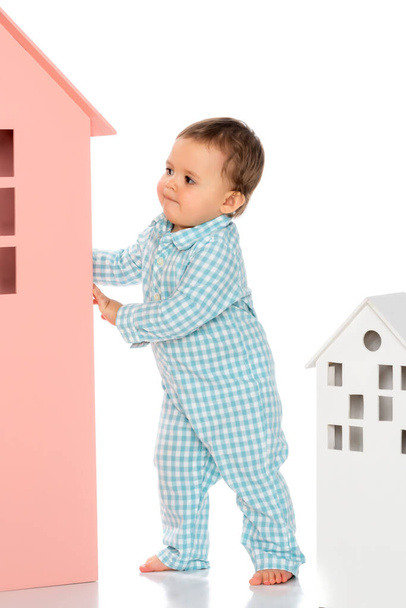 A little boy is playing in a cardboard house. - Фото, изображение