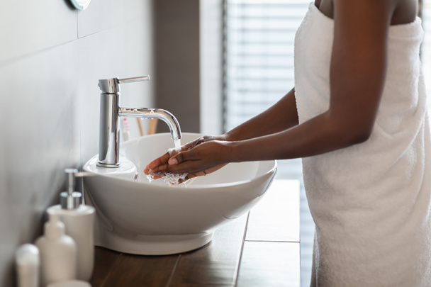 Irriconoscibile donna afro-americana lavarsi le mani in bagno - Foto, immagini