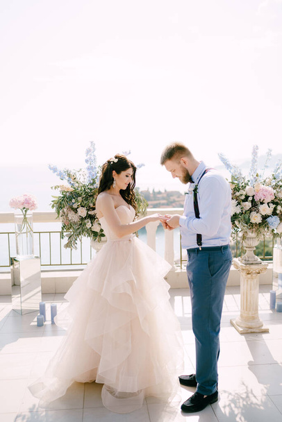 Damat, düğün töreni sırasında düğün süslemelerinin arka planına yüzüğü parmağına takar.  - Fotoğraf, Görsel