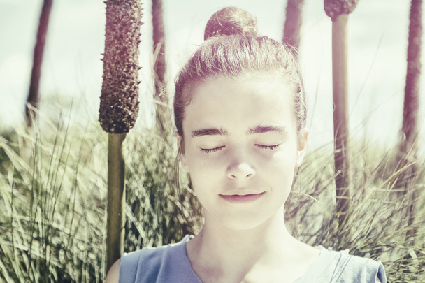 egy tinédzser lány Vintage változata meditál a nád előtt  - Fotó, kép