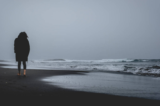 Samotna dziewczyna spacerująca po plaży i panoramiczny widok na Pacyfik z falami, horyzont i zachmurzone niebo - Zdjęcie, obraz
