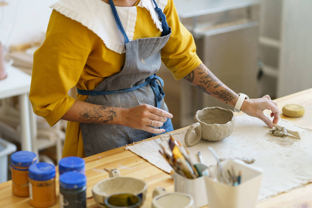 Handgefertigte Keramik: Keramikerin bereitet Details für zukünftigen Becher im Atelier vor - Foto, Bild