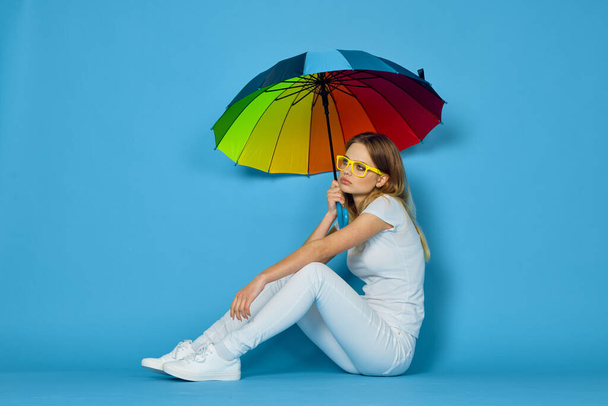 fashionable woman with umbrella rainbow colors posing blue background - Foto, afbeelding