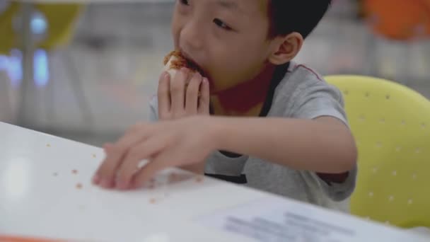 小さな子供は食べるためにテーブルの上にクリスピーな肌を収集するまでおいしいフライドチキンを食べる - 映像、動画