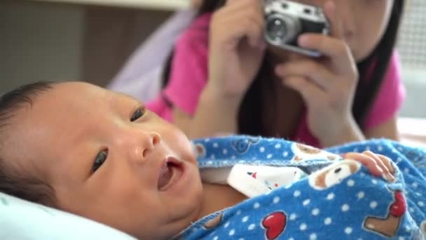 Cerca de la hermana tomar la foto del bebé recién nacido en el dormitorio - Imágenes, Vídeo