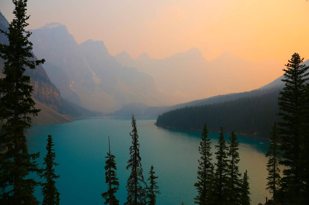 Озеро Иконик Морейн в Банфском национальном парке, Альберта, Канада. Выстрел летом 2021 года был туманным в результате дыма от лесных пожаров. - Фото, изображение