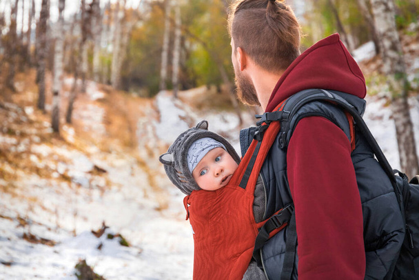 Babywearing paseo otoñal de un padre y su hijo pequeño en un cabestrillo. - Foto, imagen