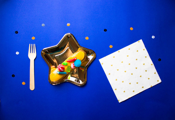 Десерт на Хелловін - клерк на золотій зірковій тарілці, виделці, серветці на синьому фоні
. - Фото, зображення