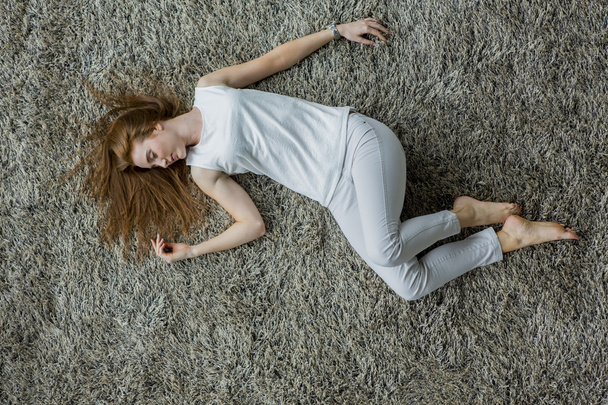 Woman lying on the carpet - 写真・画像