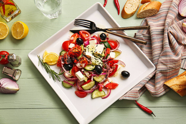Тарелка с вкусным греческим салатом на деревянном фоне - Фото, изображение