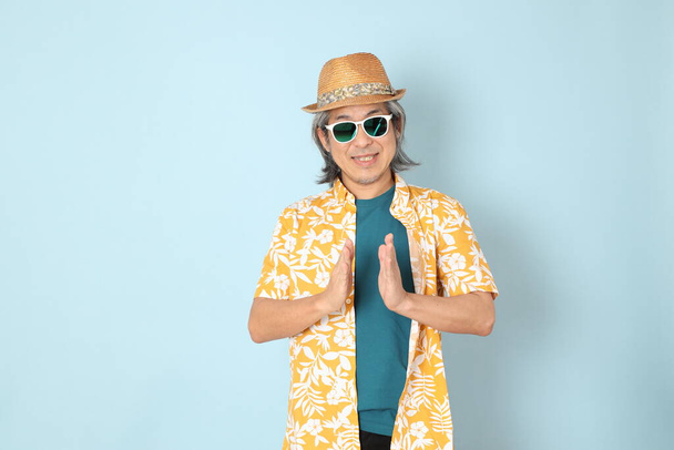 The senior Asian man wearing summer dressed standing on the blue background. - Zdjęcie, obraz