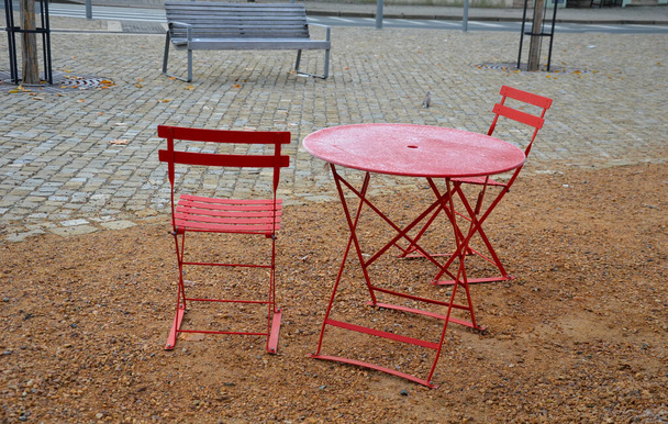 червоні стільці і круглі столи в кафе на забитій площі з піщаною поверхнею ущільненого гравію. все зроблено зі світлого матеріалу, який можна складати і чистити щоночі. льодовикове глазурування
 - Фото, зображення