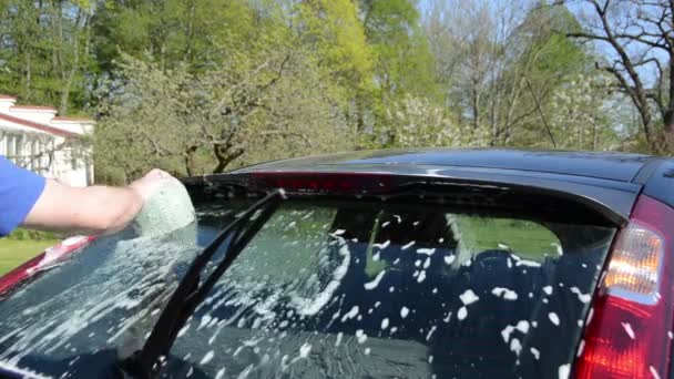 Primer plano del hombre con esponja jabonosa limpiar lavar el vidrio del coche
 - Metraje, vídeo