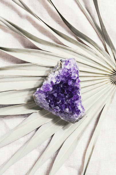 ヤシの葉の上に紫色のアメジスト結晶を捨て、儀式用の魔法の岩、魔女、精神的な練習、瞑想のための魔法の岩。.  - 写真・画像