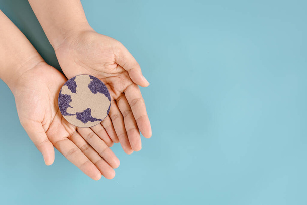 Uratuj Ziemię i Koncepcję Zmian Klimatu, Chroń Ziemię dla Zrównoważonych Zasobów. Kobiece ręce trzymające symbol globu na odizolowanym niebieskim tle. Ochrona Ziemi przed przyszłym zrównoważonym rozwojem - Zdjęcie, obraz