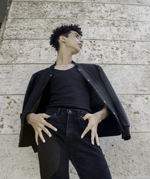A low angle shot of a Hispanic male in a black outfit posing on the streets in Old Havana, Cuba - 写真・画像