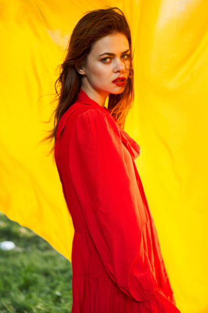 красивая женщина в красном платье природа желтая ткань на заднем плане - Фото, изображение
