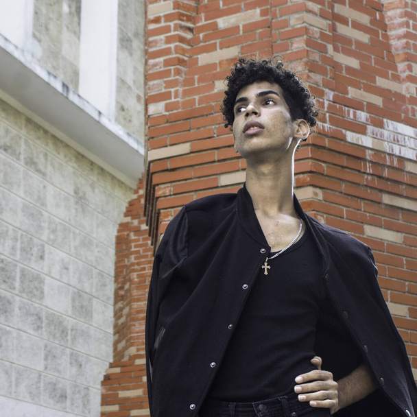 A young Hispanic male in a black outfit posing on the streets in Old Havana, Cuba - Zdjęcie, obraz